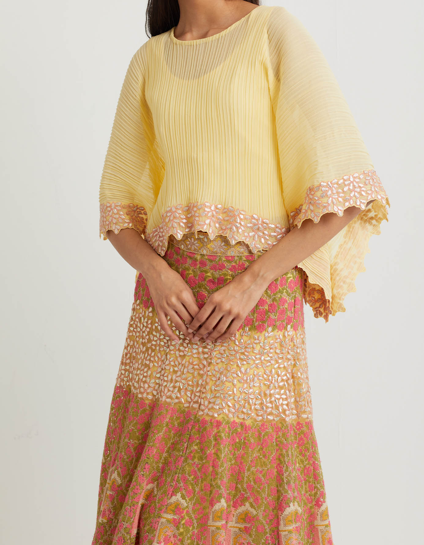 Yellow cross stitch embroidered skirt in landscape motif paired with crinkle georgette poncho top in gota embroidery