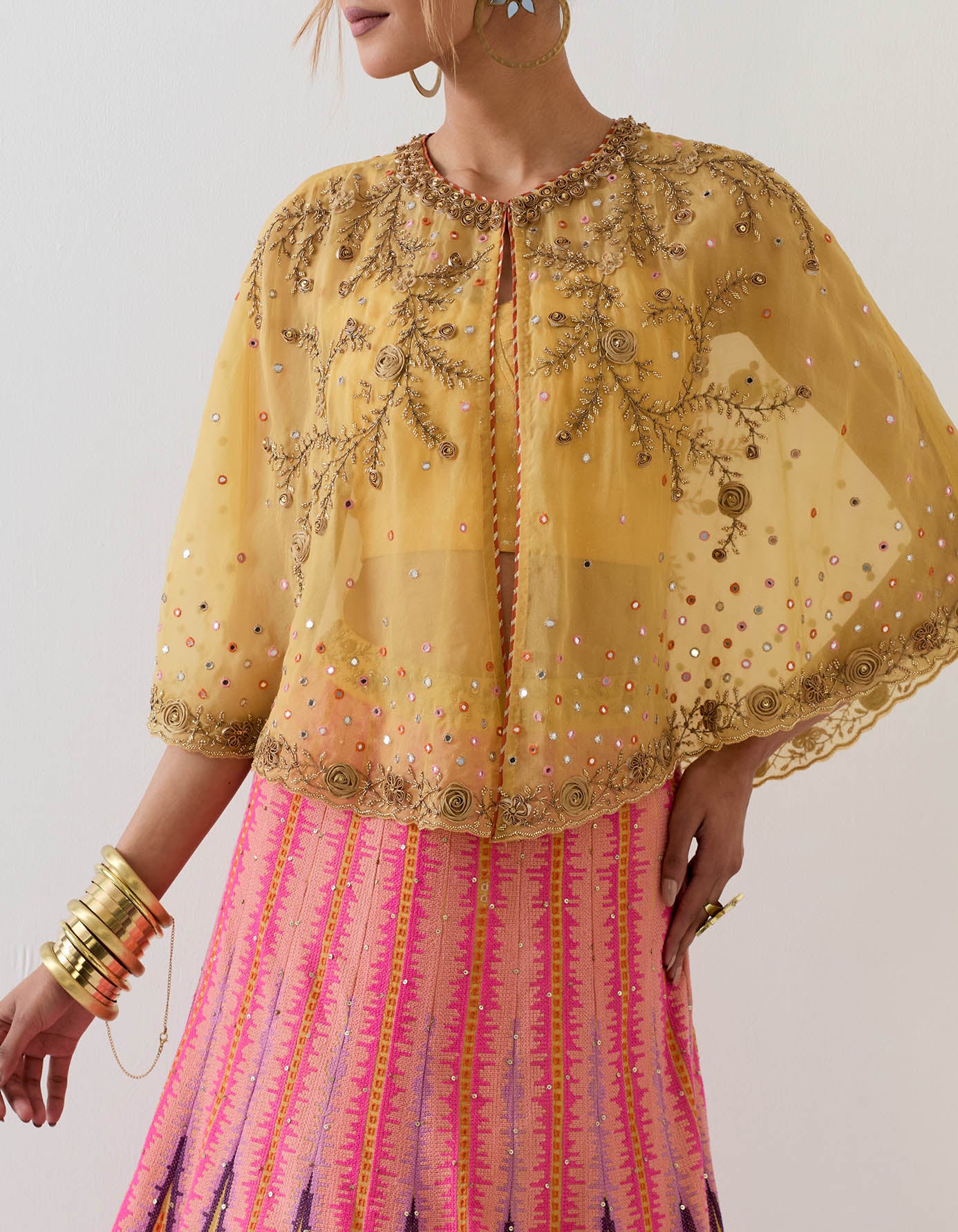 Mustard yellow organza circular cape paired with cross stitch embroidered skirt and foil printed stretch bustier