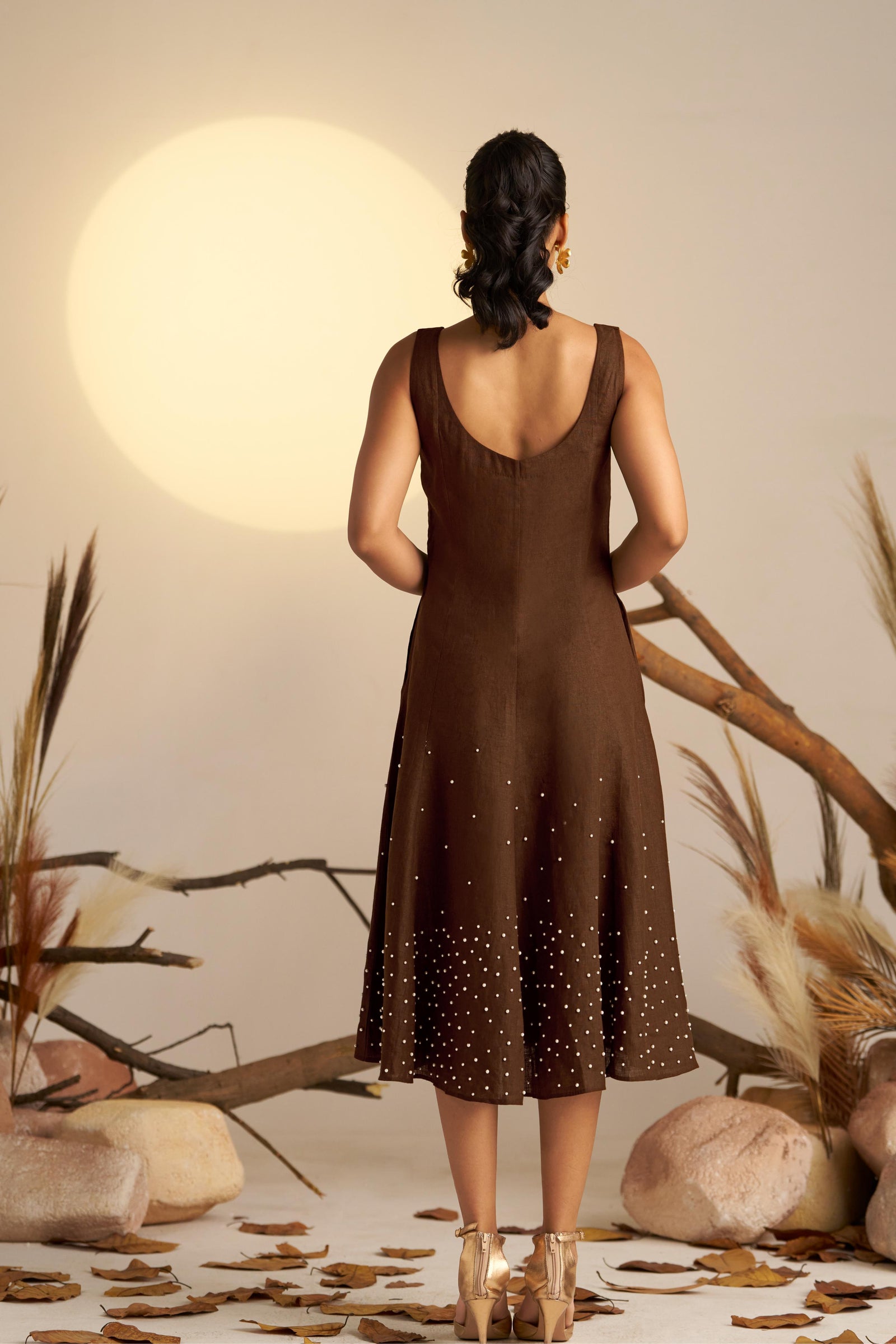 A Stunning Sleeveless Dress In Rich Sepia, Featuring Delicate Pearl Embellishments Along The Hem For A Touch Of Elegance