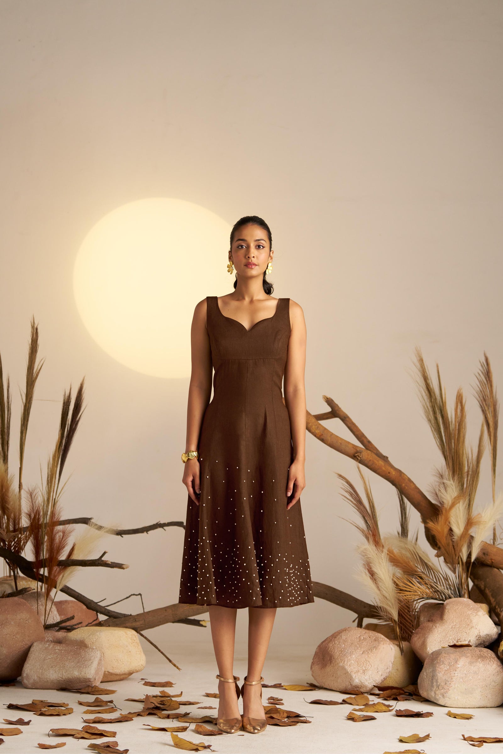 A Stunning Sleeveless Dress In Rich Sepia, Featuring Delicate Pearl Embellishments Along The Hem For A Touch Of Elegance
