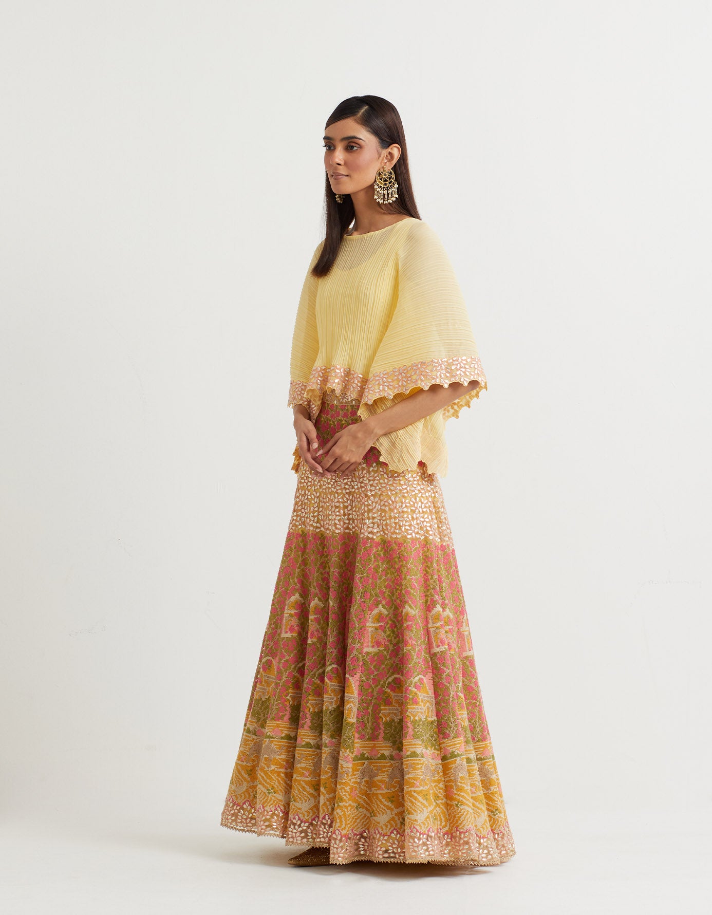 Yellow cross stitch embroidered skirt in landscape motif paired with crinkle georgette poncho top in  gota embroidery