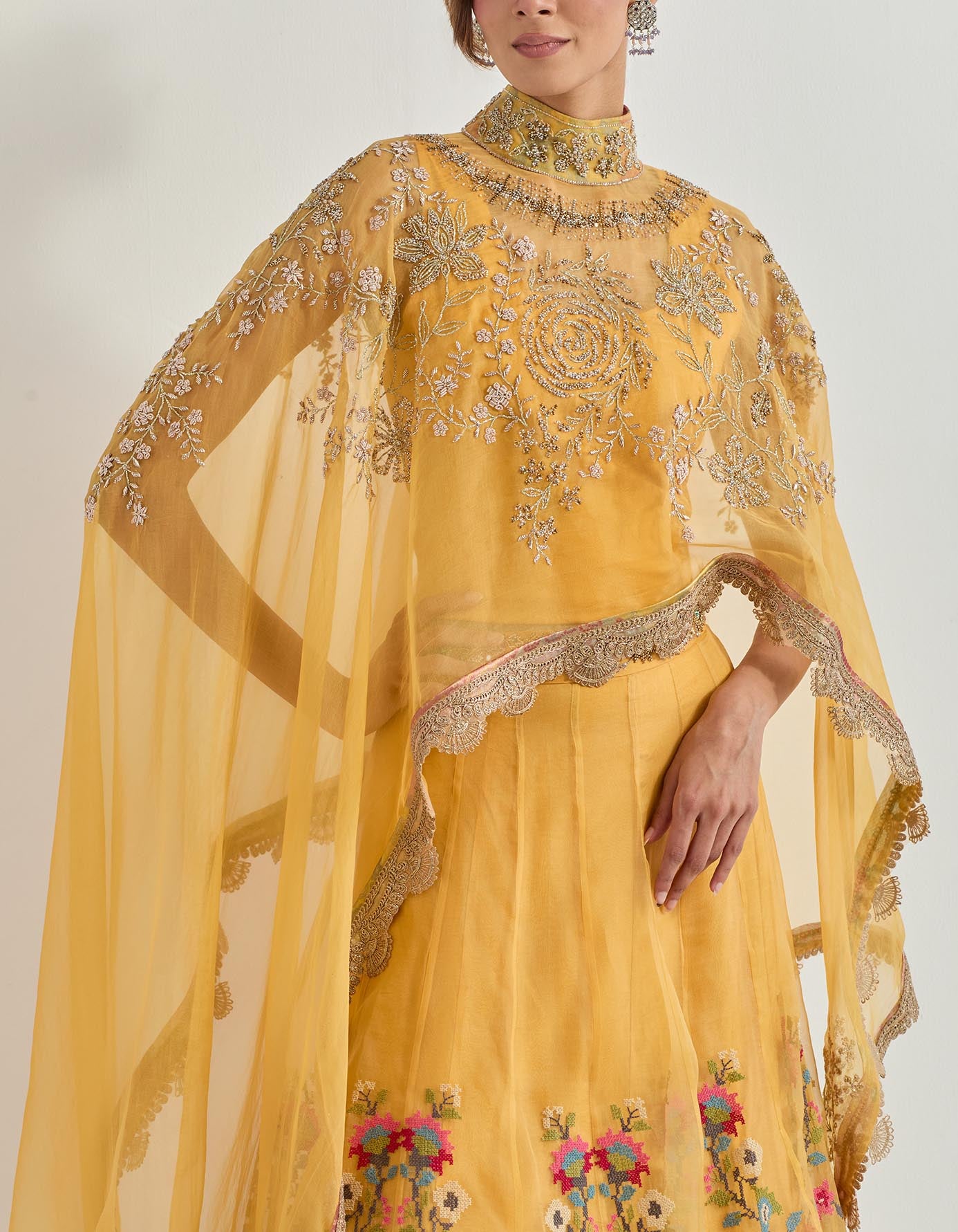 Hand emebllished dupatta cape paired with cross stitch embroidered skirt with frill detail at the hem