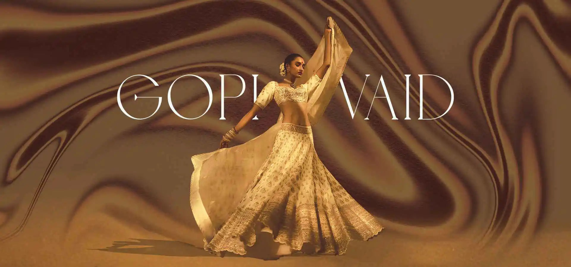 Woman in traditional attire with 'Gopi Vaid' text on a brown fabric background